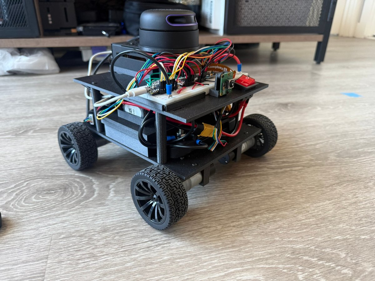 Sentinel robot on a wood floor: a two-deck 3D-printed four-wheel chassis with a lidar on top, a Raspberry Pi camera, breadboard wiring, and a red power switch